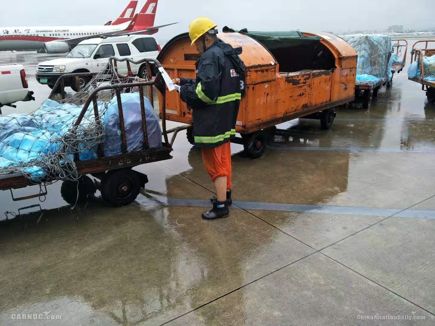 東(dong) 航虹橋裝卸服務中心員工正在風雨中核對拖車中裝載的行李和貨物清單。供圖/東(dong) 航