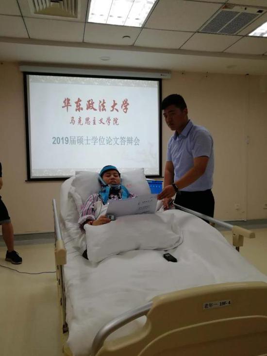程豔芳正在進行答辯，弟弟程浩幫她舉(ju) 著論文 受訪者供圖