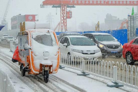  2020年2月14日，北京迎來降雪天氣，快遞小哥忙著送貨。圖 | 視覺中國